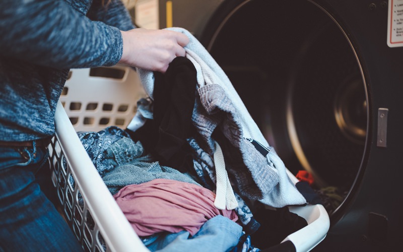 Lifestyle image of a woman pulling laundry out of the dryer